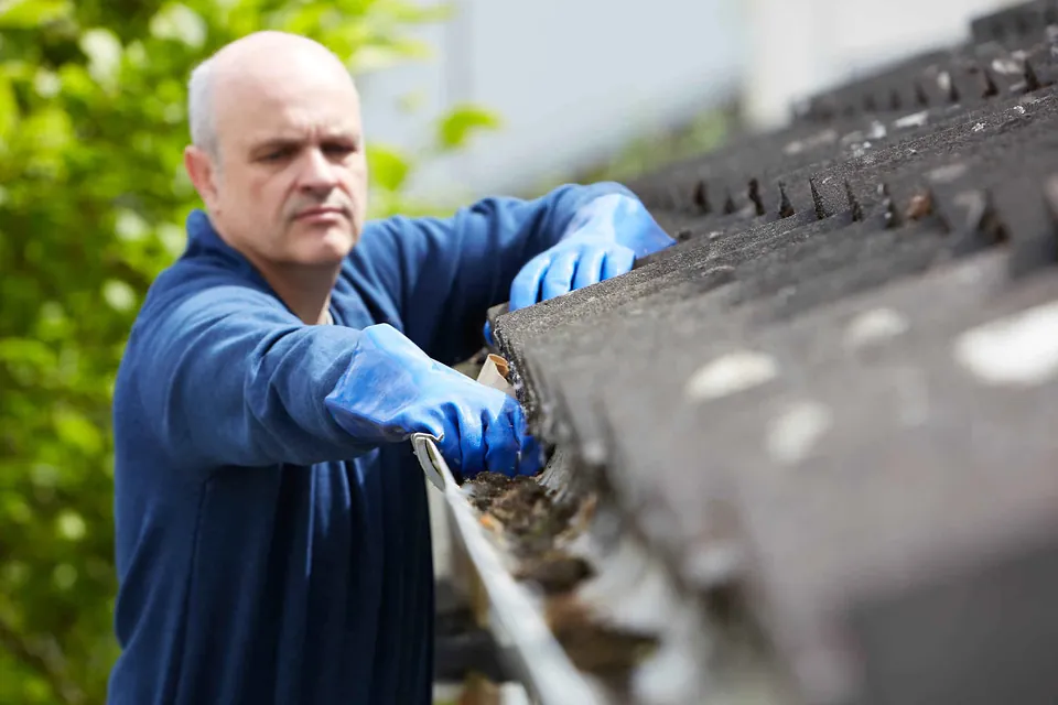 Čištění okapového žlabu od listí při kontrole střechy