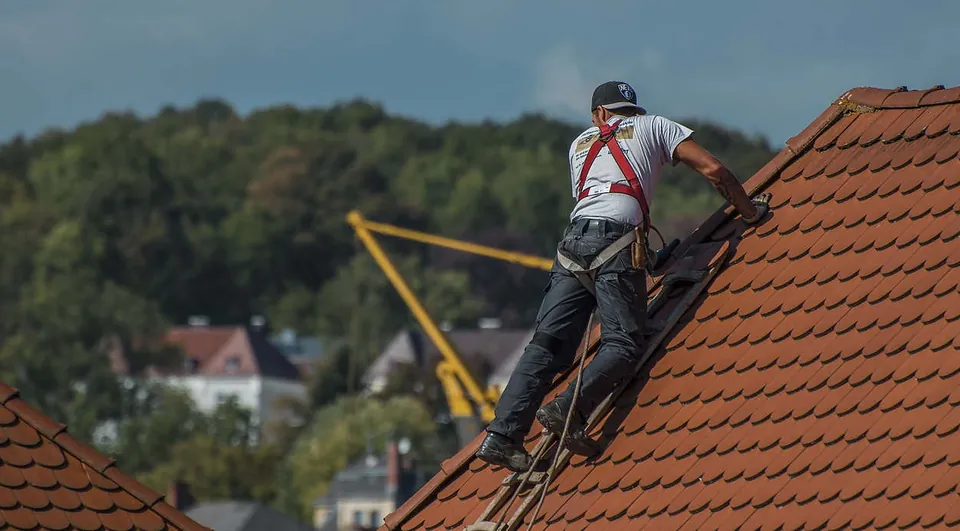 Pokrývač jištěný postrojem při práci na taškové střeše